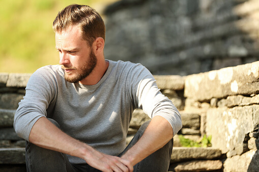 man sitting on a step and showing signs of alcoholism