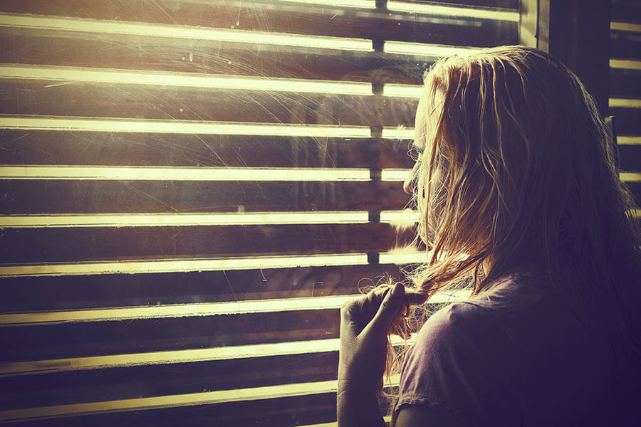 woman looking out window wonders about opioid epidemic