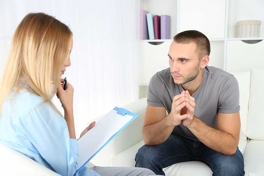 A young man talks with a counselor about alcohol treatment
