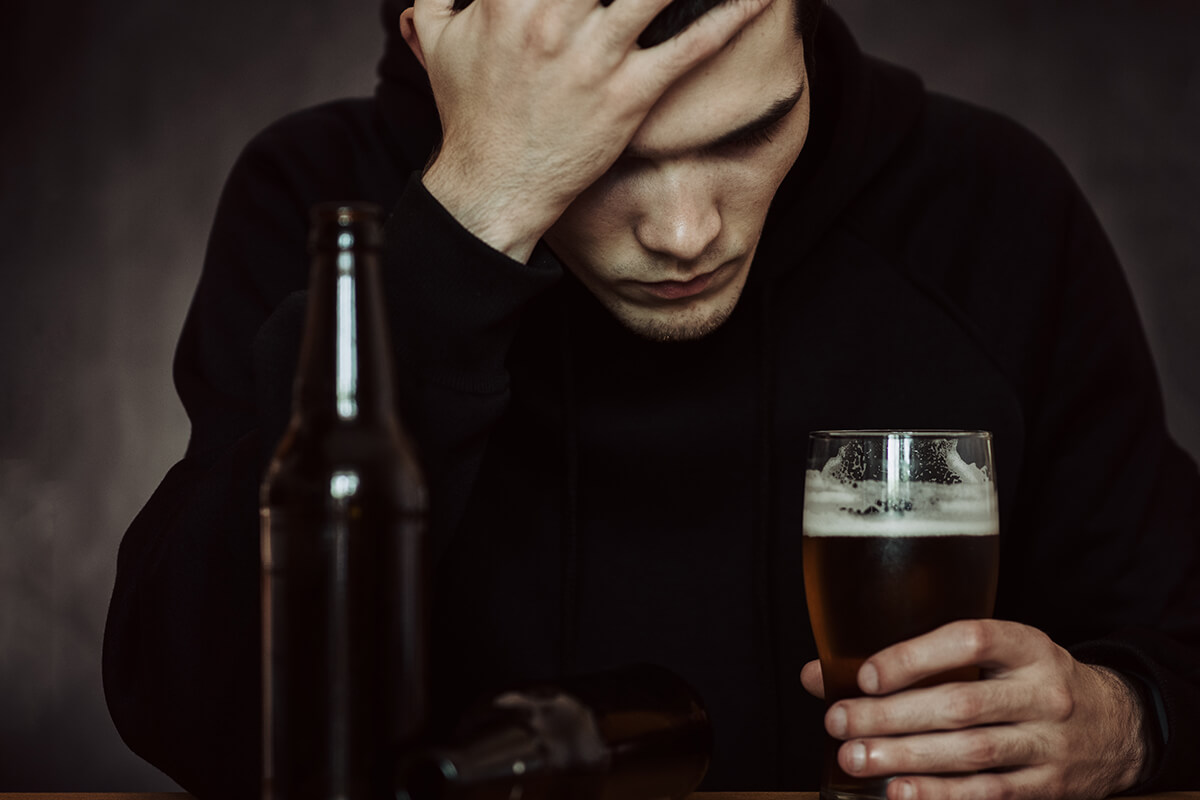 man holding his head while drinking unaware of the alcohol abuse definition