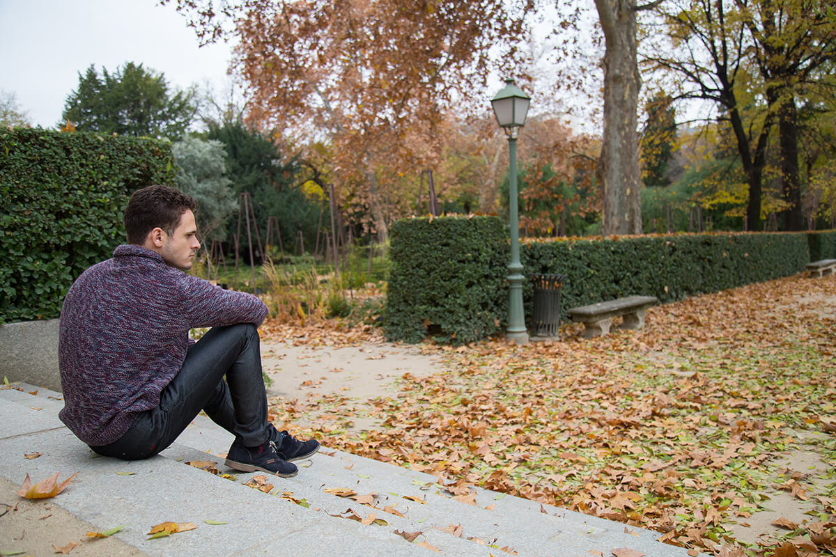 man sitting on steps alone wondering how to overcome addiction