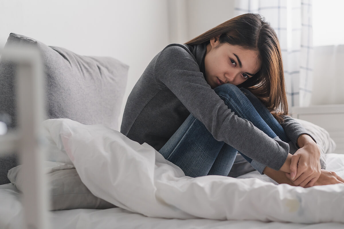 woman sitting in bed showing Alcoholism Symptoms