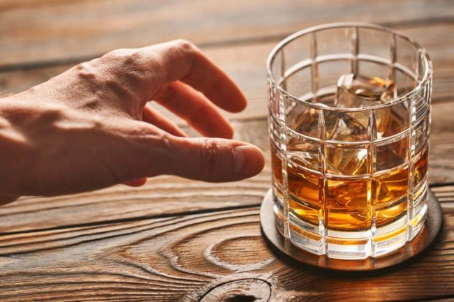 hand reaching for alcohol despite the San Antonio alcohol abuse statistics