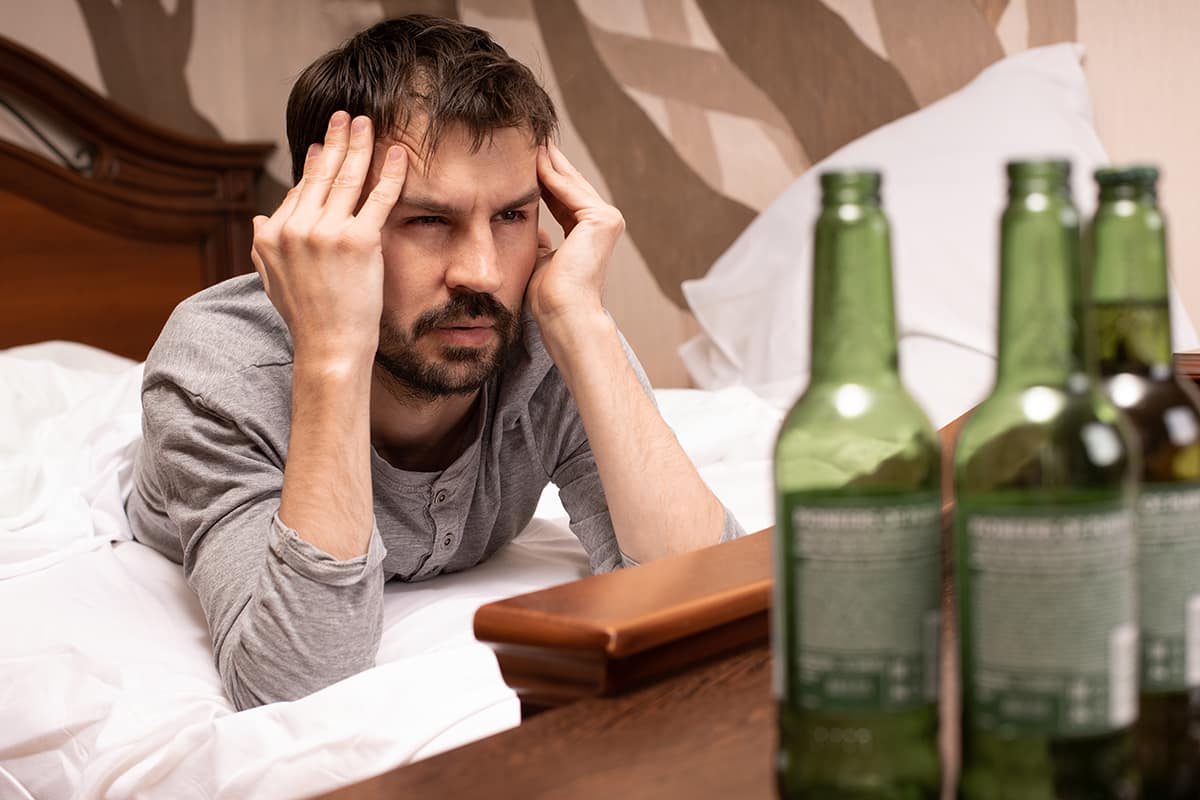 man rubbing his temples struggling with alcohol and anxiety