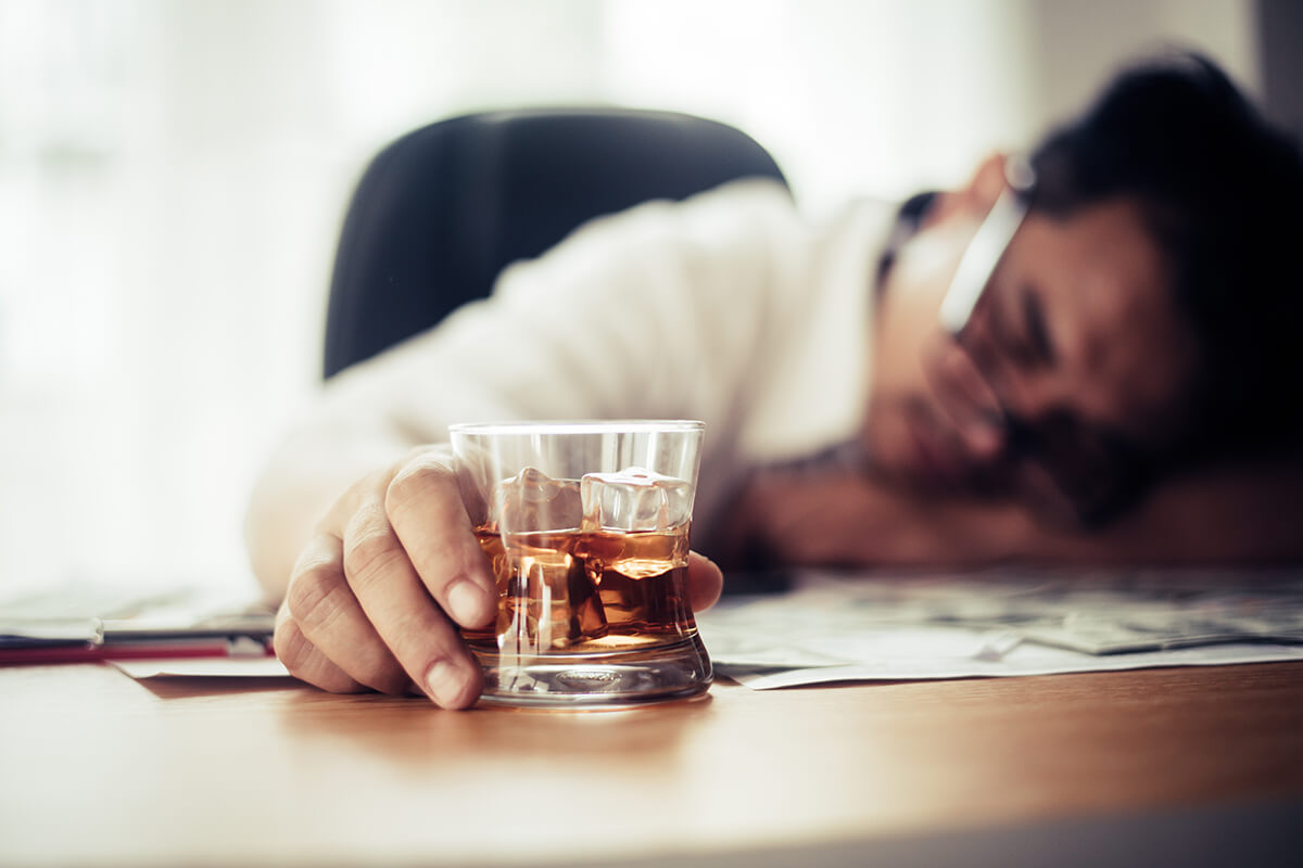 man sitting with a glass in his hand is wondering, am I an alcoholic?