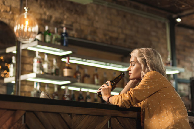 woman with a drink at the bar wonders is alcohol a stimulant