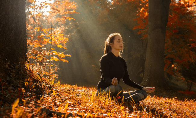woman is practicing mindfulness based relapse prevention by meditating in the woods