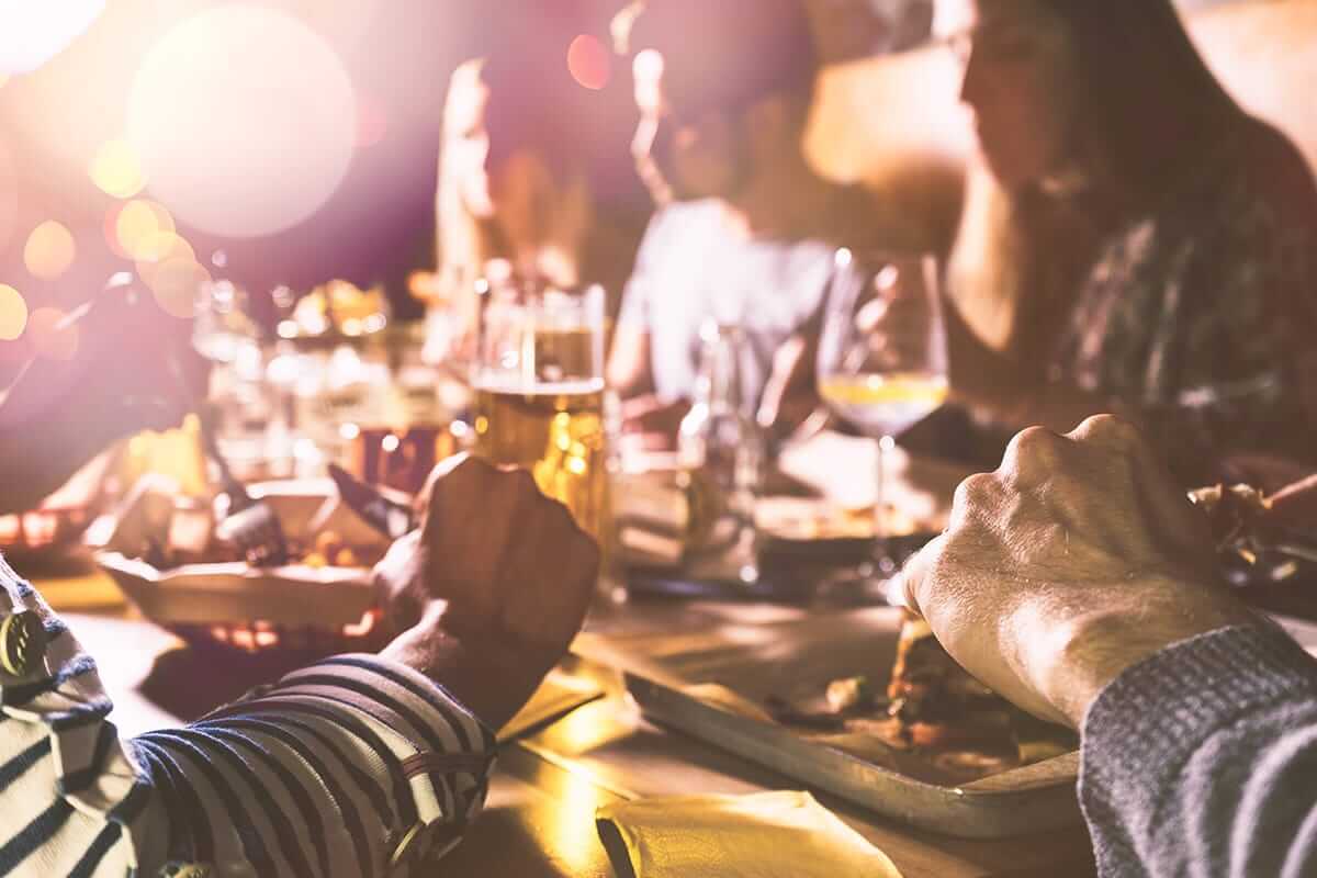a group of friends eating food and social drinking vs alcoholism