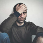 man holding head struggling with heroin addiction symptoms