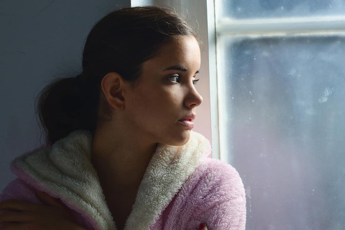 woman looking out window struggling with types of mental illnesses