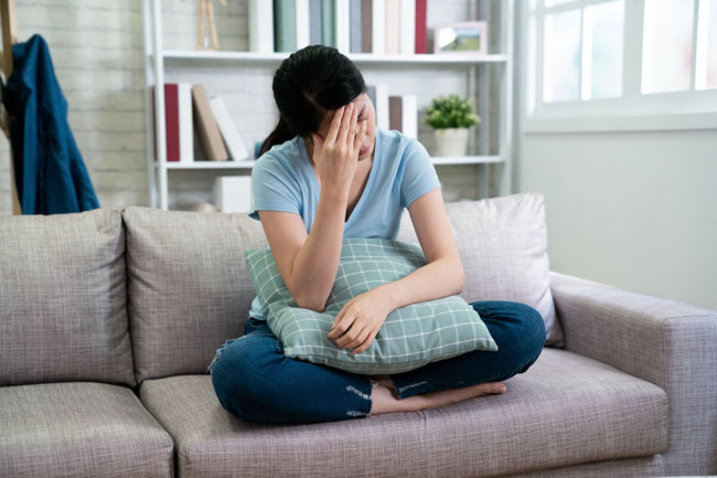 stressed woman on couch wondering do I need addiction treatment