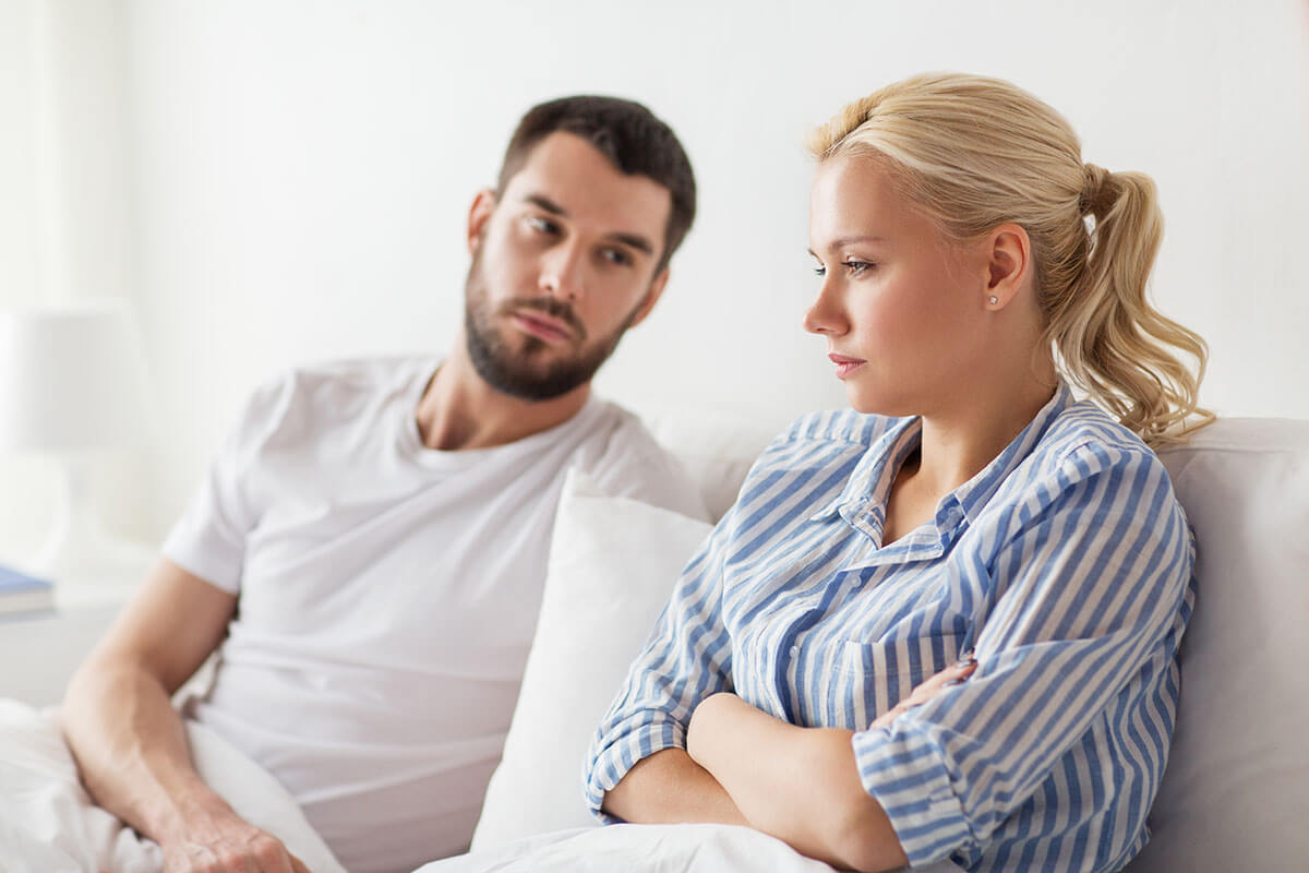 woman with arms crossed in bed next to man while thinking is my loved one an alcoholic