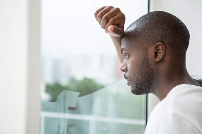 pensive man looking through window unaware of myths about drugs