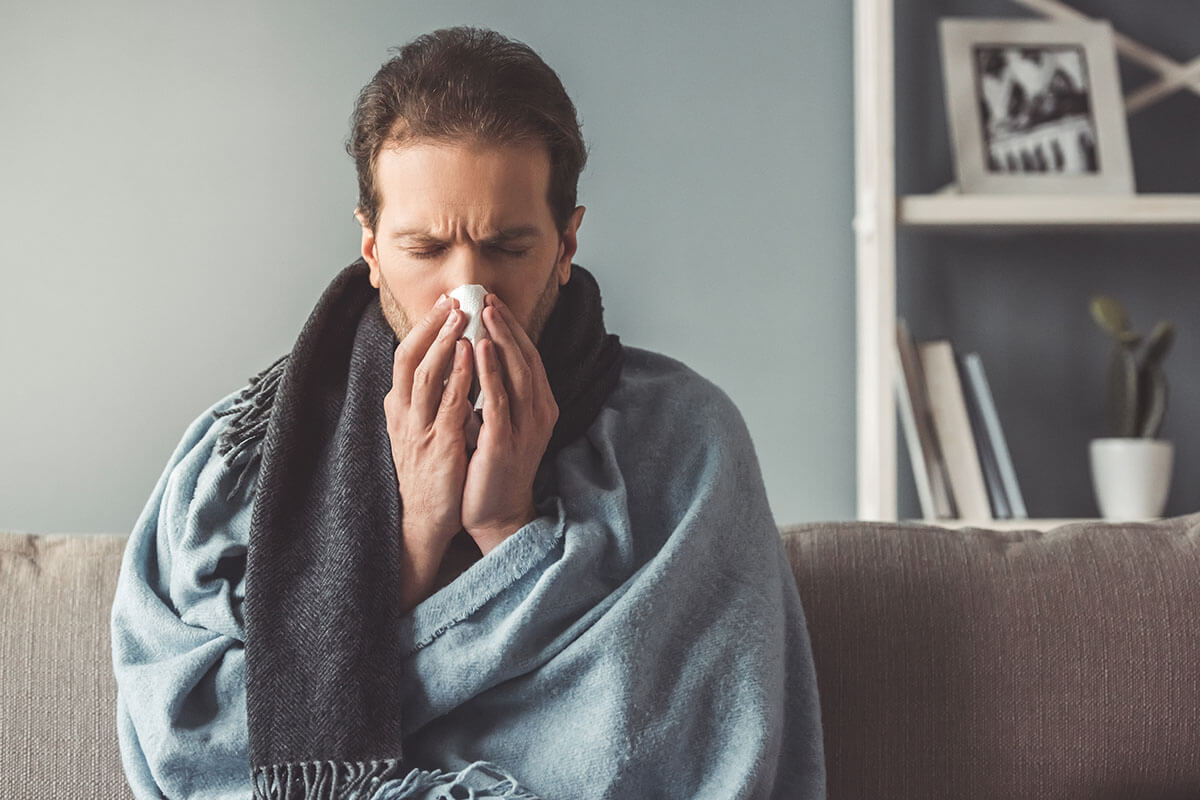 sneezing man on couch worried about addiction and your physical health