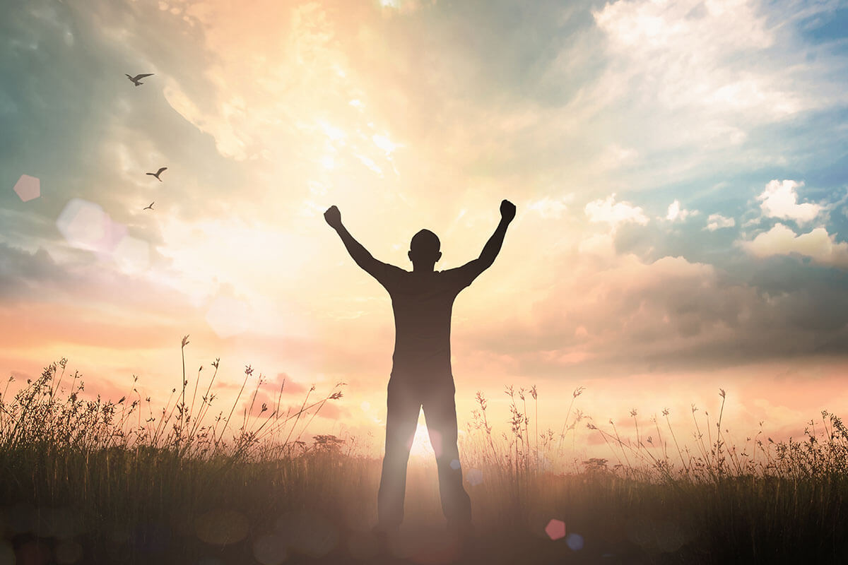 man raising arms in jubilation thanks to alcohol addiction recovery