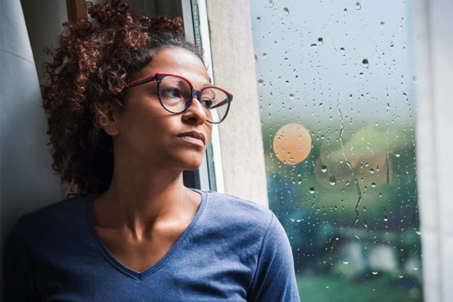woman staring out rainy window needing Depression Treatment during coronavirus