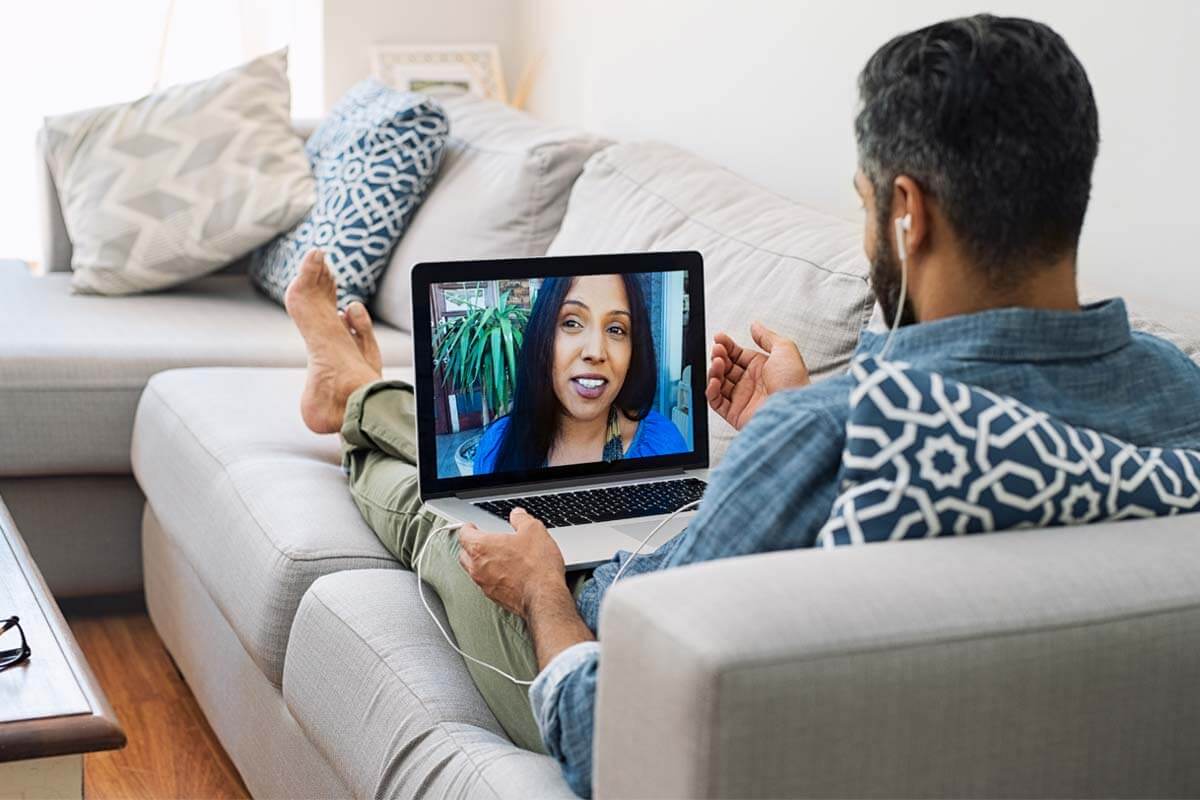 man on couch using laptop for Online Addiction Treatment