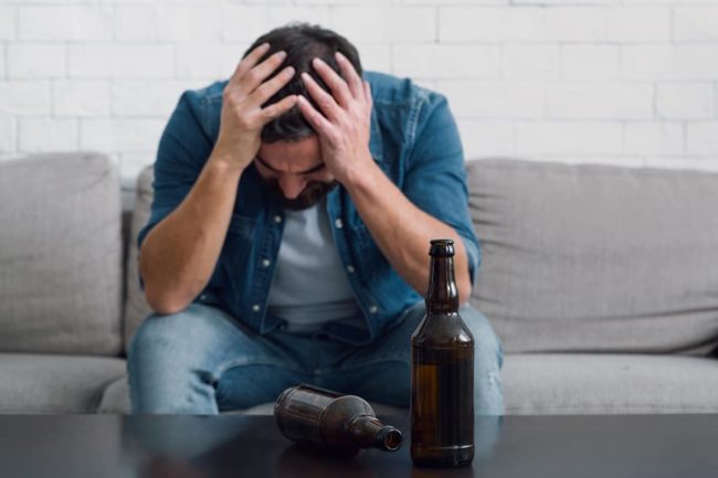 man holding his head feeling the effects of alcohol on the brain