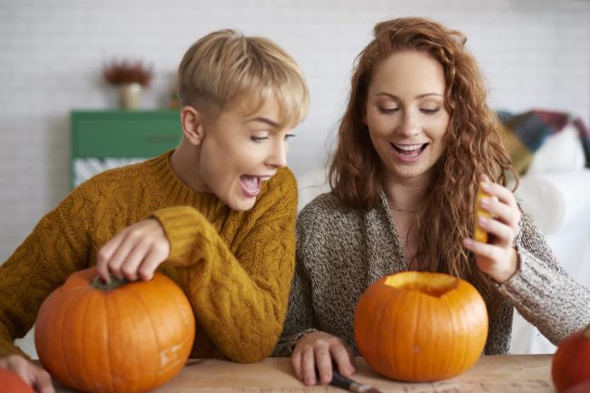 two women carve pumpkins during a sober halloween celebration