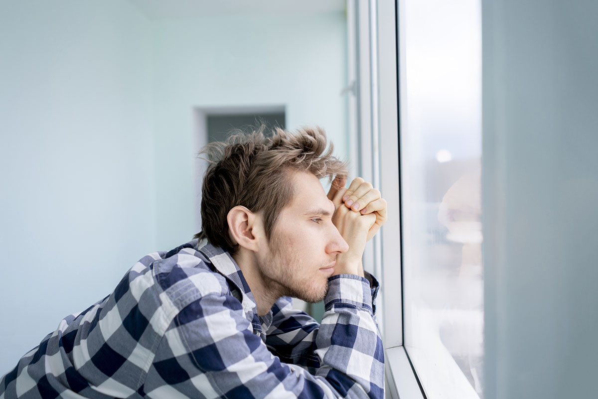 man staring out window experiencing drug overdose symptoms